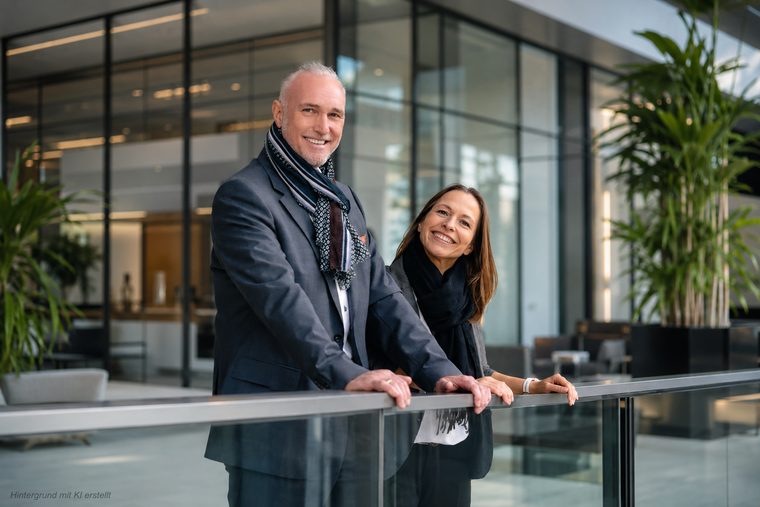 Volker Loibl und Melanie Reuß von apollo consulting an der Glasbrüstung im Bürogebäude